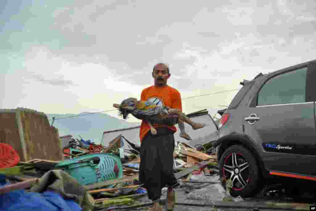 A man carries the body of a child who was killed in the tsunami in Palu, Central Sulawesi, Indonesia,, Sept. 29, 2018.