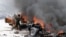 A policeman runs through burning vehicles at the scene of an explosion near the presidential palace in Mogadishu, Somalia, March 18, 2013.