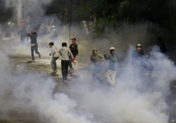 Student protesters run from tear gas fired by riot police during a clash in Jakarta, Indonesia, Sept. 30, 2019.