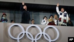 Thomas Bach, prezidan Komite Entènasyonal Olenpik la, ak Prezidan Kore di Sid la, Moon Jae-in, ki t ap salye piblik la pandan seremoni fèmti Je Zolenpkik d Ivè 2018 yo nan Pyeongchang, nan Kore di Sid. (Foto: 25 fevriye 2018).