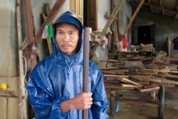 A local man wearing a raincoat stands near a home that was recently flooded in Quang Tri.