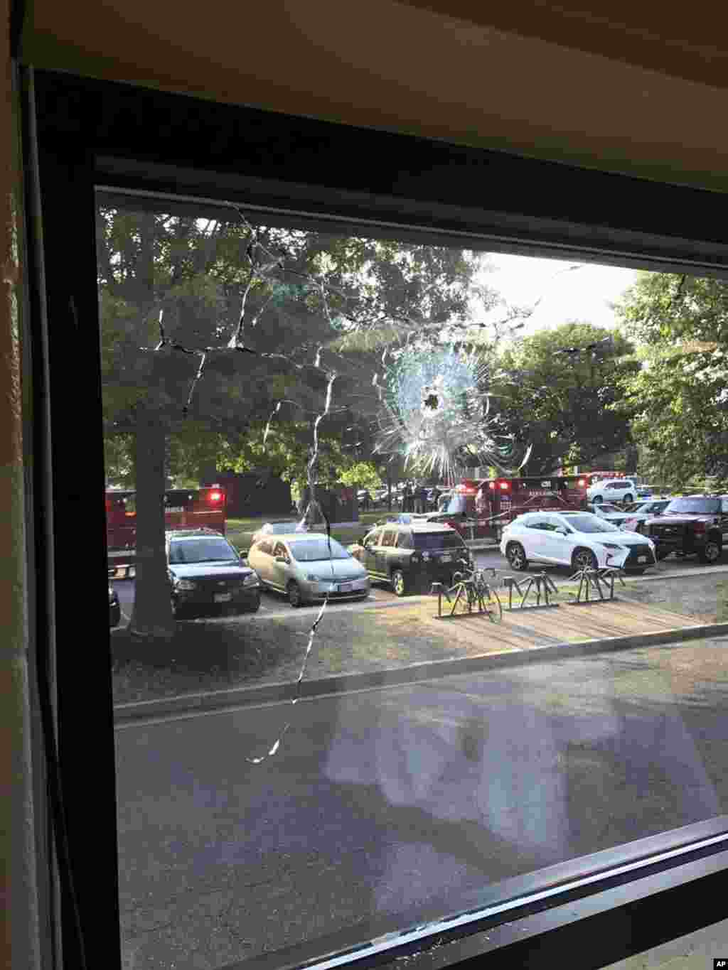 Emergency personnel are seen through a window with a bullet hole in Alexandria, June 14, 2017.