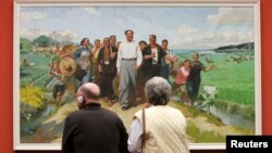 FILE - Gallery visitors view 'Chairman Mao inspects the Guangdong Countryside' by Chinese artist Chen Yanning at the 'Mahjong' exhibition of Contemporary Chinese Art at the Kunsthalle museum in Hamburg, Germany.