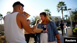 Kathryn Quintin of the policy and education group Young Invincibles, right, offers free pizza to students waiting in line to vote at the ASU Palo Verde West polling station during the U.S. midterm elections in Tempe, Ariz.. Nov. 6, 2018. 