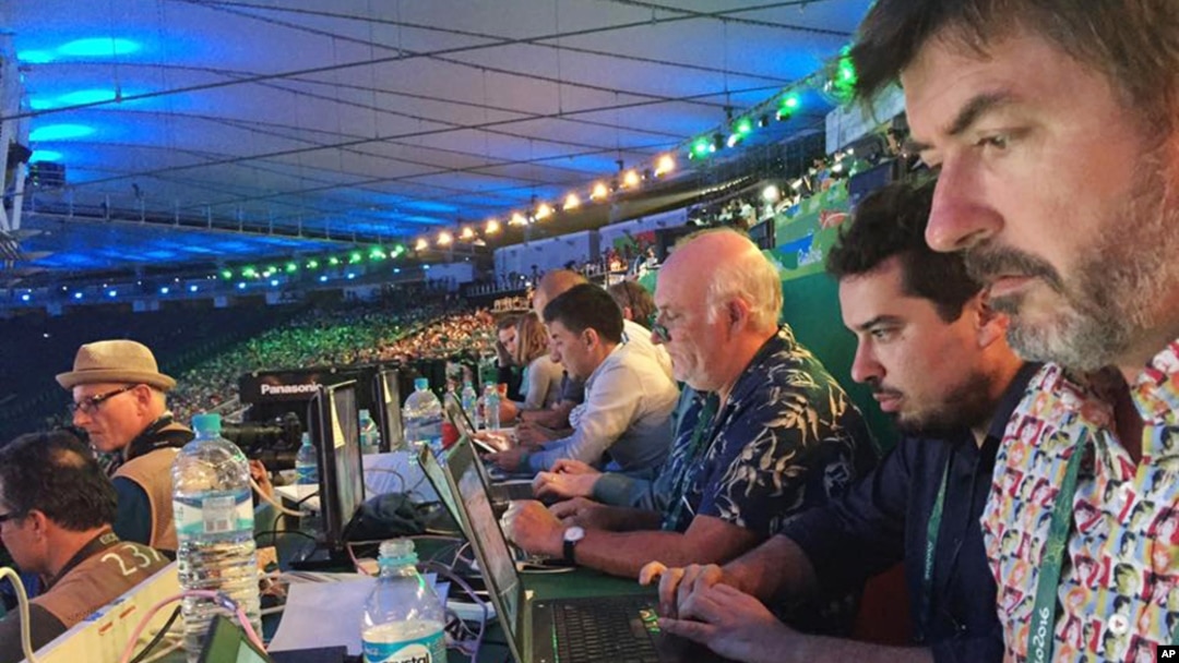 In this Aug. 5, 2016 photo, Associated Press writers John Leicester, right, and Mauricio Savarese, second from right, work at the press table in the Maracana Stadium during the opening ceremony of the Summer Olympics in Rio de Janeiro, Brazil. 
