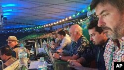 In this Aug. 5, 2016 photo, Associated Press writers John Leicester, right, and Mauricio Savarese, second from right, work at the press table in the Maracana Stadium during the opening ceremony of the Summer Olympics in Rio de Janeiro, Brazil. 