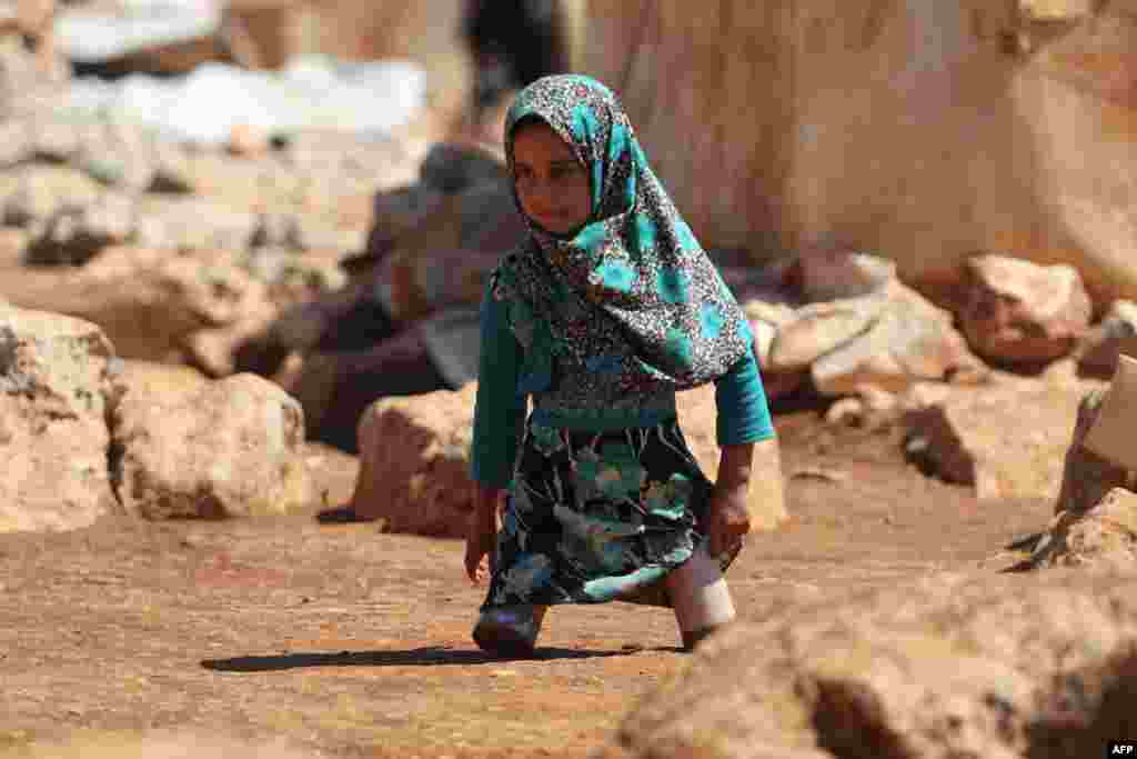 Eight year-old Maya Mohammad Ali Merhi walks using prosthetic legs made by her father from tin cans in a camp for displaced people, in the northern Syrian province of Idlib.