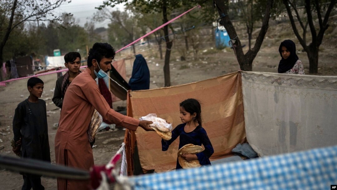 Afganos distribuyen donaciones de alimentos en un campamento de desplazados internos en Kabul, Afganistán, el 13 de septiembre de 2021. 
