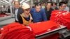 In this file photo taken on Aug. 30, 2017, Prime Minister Hun Sen, center, leans over a garment worker during a visit to a factory outside of Phnom Penh, Cambodia. 