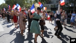 Para pengunjung mengenakan busana era Perang Dunia II dan menari di jalan dalam perayaan 75 tahun pembebasan Perancis dari pendudukan Nazi, di Paris, 25 Agustus 2019. (Foto: AP)