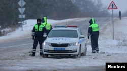 Traffic police officers stand guard on a road near the crash site of the Russian Ilyushin Il-76 military transport plane outside the village of Yablonovo in the Belgorod Region, Russia Jan. 24, 2024. 