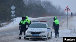 Oficiales de la policía de tránsito hacen guardia en una carretera cerca del lugar del accidente del avión de transporte militar ruso Ilyushin Il-76 en las afueras de la aldea de Yablonovo en la región de Belgorod, Rusia, el 24 de enero de 2024. 