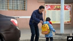 In this Dec. 18, 2017, photo, Chinese labor activist Hua Haifeng, adjusts the backpack of his son Bo Bo, 4, as he takes him to school on the outskirts of Xiangyang in central China's Hubei Province. Apple Inc. and Ivanka Trump's brand both rely on Chinese suppliers that have been criticized for workplace abuses. But they've taken contrasting approaches to dealing with supply chain problems. When Apple learned thousands of student workers at an iPhone supplier had been underpaid, it helped them get their money back. After three men investigating labor abuses at factories that made Ivanka Trump shoes were arrested last year, neither Ivanka Trump nor her brand spoke out.
