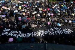 Protesters carrying umbrellas and a huge banner reading "Hong Kong police deliberate murder" march in Hong Kong, Oct. 20, 2019.