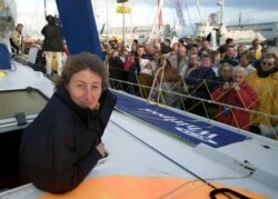 FILE - French skipper Catherine Chabaud stands on her boat as visitors pass by at Les Sables D'Olonne harbor on France's Atlantic coast on Nov. 2, 2000.