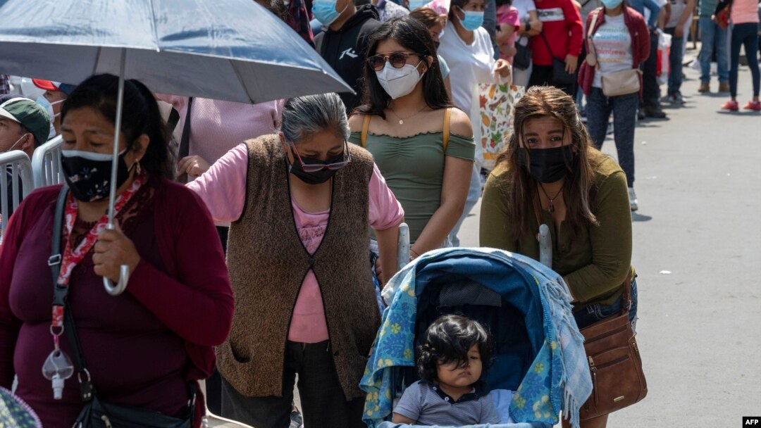 Peruanos hacen fila para hacerse exámen y vacunas en un centro de salud improvisado en una calle del centro de Lima el 5 de enero de 2022.