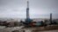 FILE - An oil derrick is seen at a fracking site outside of Williston, North Dakota.