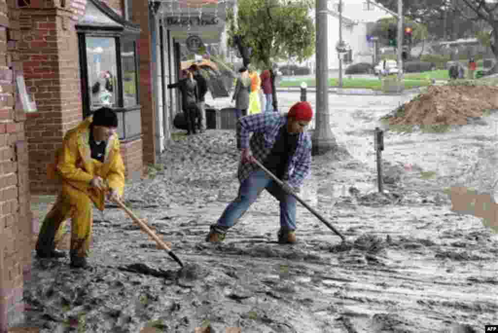 Workers shovel mud out onto Pacific Coast Highway from the entrance to the Laguna Cinemas in Laguna Beach, Calif. Wednesday, Dec. 22, 2010. Downtown Laguna Beach was closed by up to 4 feet of storm runoff, which receded but left streets awash in mud. Aft