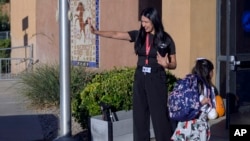 Principal Rosangela Montoya waves goodbye to parents as students arrive at school, at Algodones Elementary School in Algodones, New Mexico, Oct. 1, 2024.