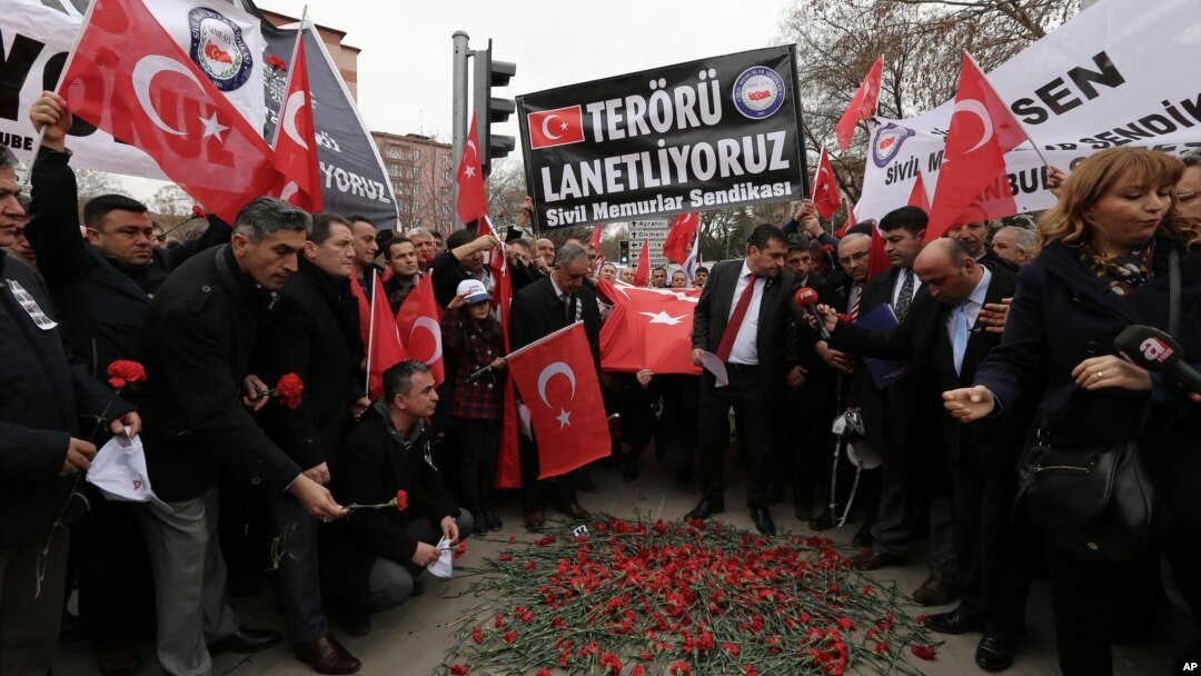 Turkish civil servants hold a banner that reads "We condemn terrorism" as they lay carnations at the site of Wednesday's explosion that killed 28 people in Ankara, Feb. 20, 2016.