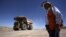 FILE - A worker checks Chile's Esperanza open pit copper mine as a truck travels along a road near Calama town, about 1,650 km (1,025 miles) north of Santiago, March 30, 2011. 