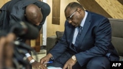 L’opposant congolais Jean-Pierre Bemba (D) examine les papiers pour s’inscrire aux élections présidentielles du 23 décembre prochain, au bureau de la Commission électorale indépendante, à Kinshasa, le 2 août 2018.