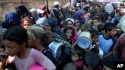 FILE - Palestinians line up for food distribution in Deir al-Balah, Gaza Strip, on Oct. 17, 2024.