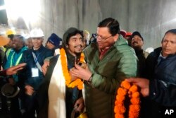 This handout photo shows Pushkar Singh Dhami, right, Chief Minister of the state of Uttarakhand, greeting a worker rescued from the site of a collapsed tunnel on Nov. 28, 2023. (Uttarakhand State Department of Information and Public Relations via AP)