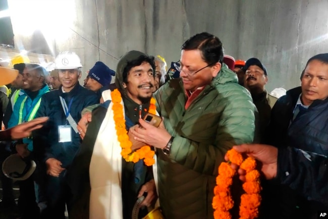 This handout photo shows Pushkar Singh Dhami, right, Chief Minister of the state of Uttarakhand, greeting a worker rescued from the site of a collapsed tunnel on Nov. 28, 2023. (Uttarakhand State Department of Information and Public Relations via AP)