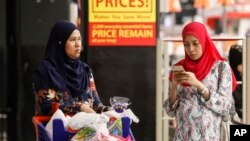 FILE - A Malaysian Muslim woman checks her mobile phone while shopping at a mall outside Kuala Lumpur, Malaysia, Aug. 18, 2015. 