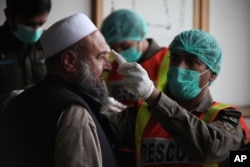 A health official of an emergency rescue service checks the body temperature of a government employee in Peshawar, Pakistan, March 12, 2020.
