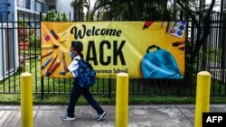 Un estudiante usa una máscara cuando ingresa a la escuela de St. Lawrence el primer día de clases después de las vacaciones de verano en el norte de Miami, el 18 de agosto de 2021.