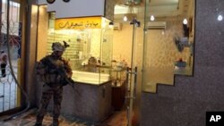 سه‌ربازێـکی عێراقی پاسه‌وانی له‌ به‌رده‌م یه‌ک له‌و دوکانه‌کانه‌ ده‌کات که‌ هێرشه‌که‌یان کراوه‌ته‌ سه‌ر، یه‌کشه‌ممه‌ 17 ی ده‌ی 2010