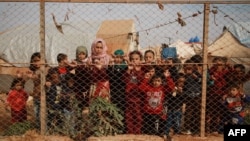 Anak-anak pengungsi Suriah berdiri di balik pagar di luar tenda penampungan mereka di desa Kafr Lusin, kawasan utara pedesaan Idlib, dekat perbatasan Suriah-Turki, 22 Oktober 2019. (Foto: dok).