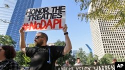 Jeremy Browning holds a sign while protesting with others outside the federal building housing the Army Corps of Engineers offices in Dallas, Nov. 15, 2016. People across the U.S. have gathered to show solidarity with opponents of the Dakota Access oil pipeline being built by Dallas-based Energy Transfer Partners.