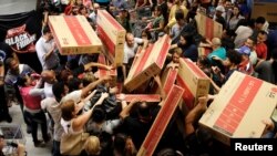 Shoppers reach for television sets as they compete to purchase retail items on Black Friday at a store in Sao Paulo, Brazil, Nov. 24, 2016. 