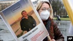 FILE - A woman holds a photo of Benjamin Briere during a rally in Paris, France, Jan. 8, 2022. 