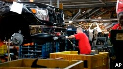 FILE- A technician tightens screws on the front bumper assembly at the Nissan Canton Assembly Plant, in Canton, Miss., March 19, 2018. 