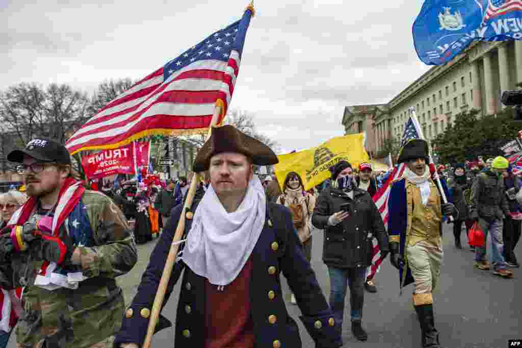 Apoiantes do Presidente dos EUA Donald Trump marcham pelas ruas da cidade enquanto se dirigem ao Capitólio em Washington DC em 6 de Janeiro de 2021. Os apoiantes de Donald Trump invadiram uma sessão do Congresso realizada a 6 de Janeiro, para certificar a vitória eleitoral Joe Biden, desencadeando caos e violência sem precedentes no coração da democracia americana&nbsp;