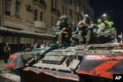 Miembros de Grupo Wagner posan con sus armas encima de un tanque en una calle de Rostov-on-Don, Rusia, el sábado 24 de junio de 2023, antes de abandonar un área en la sede del Distrito Militar del Sur.