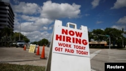 A "Now Hiring" sign advertising jobs at a hand car wash is seen along a street, as the spread of the coronavirus disease (COVID-19) continues, in Miami, Florida, May 8, 2020. 