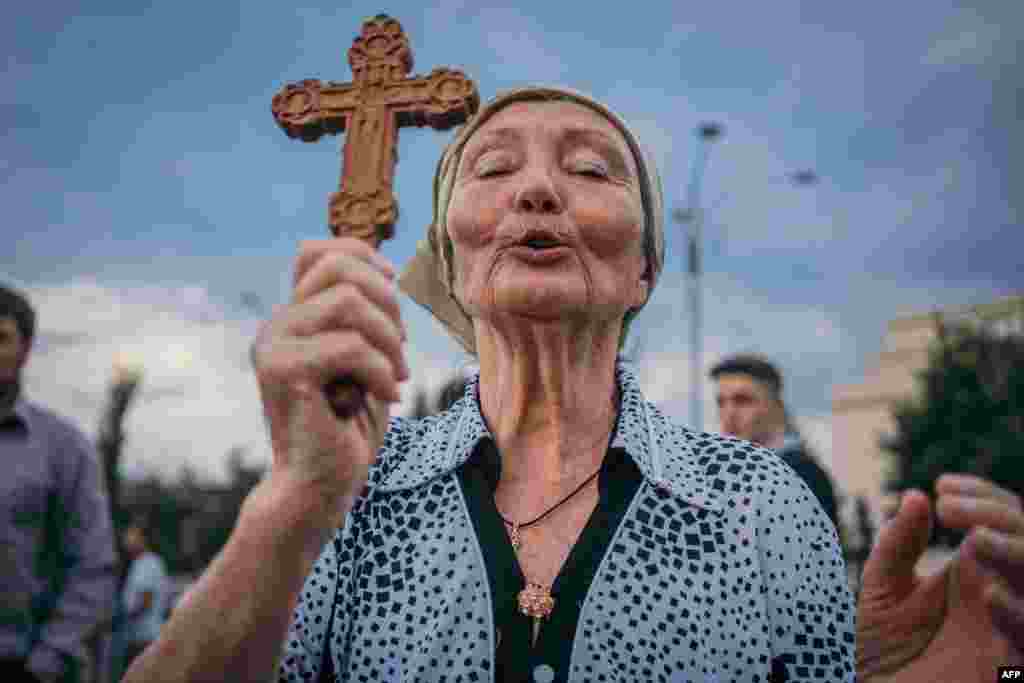 A woman prays during a protest against the Romanian government and its measures against the new coronavirus pandemic in Bucharest, July 12, 2020.