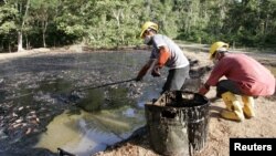 Trabajadores ecuatorianos limpian un pozo contaminado de petróleo en la zona de Taracoa, en el Amazonas.