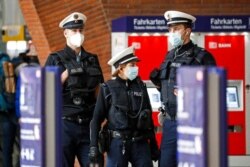 Police with face masks control the coronavirus orders at the train station in Cologne, Germany, Oct. 15, 2020. The city exceeded the important warning level of 50 new infections per 100,000 inhabitants in seven days.