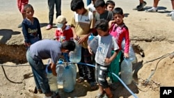 Anak-anak pengungsi Suriah mengisi botol air minum di sebuah kamp pengungsi di Lebanon timur (foto: dok). 