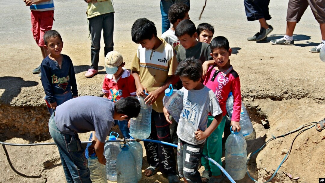 FILE - Syrian refugees fill up water bottles at a temporary refugee camp in the eastern Lebanese town of Faour near the border with Syria, August 28, 2013.