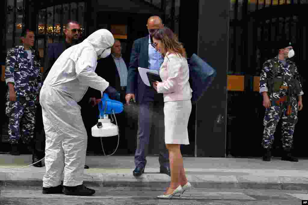 A paramedic sprays Minister of Information Manal Abdul-Samad with disinfectant as she arrives for a parliament meeting, in Beirut, Lebanon.