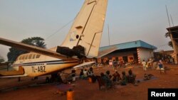A family displaced by inter-communal violence in the country sit near a plane in a camp for displaced persons at Bangui M'Poko International Airport February 20, 2014