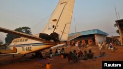 A family displaced by inter-communal violence in the country sit near a plane in a camp for displaced persons at Bangui M'Poko International Airport, Feb. 20, 2014.
