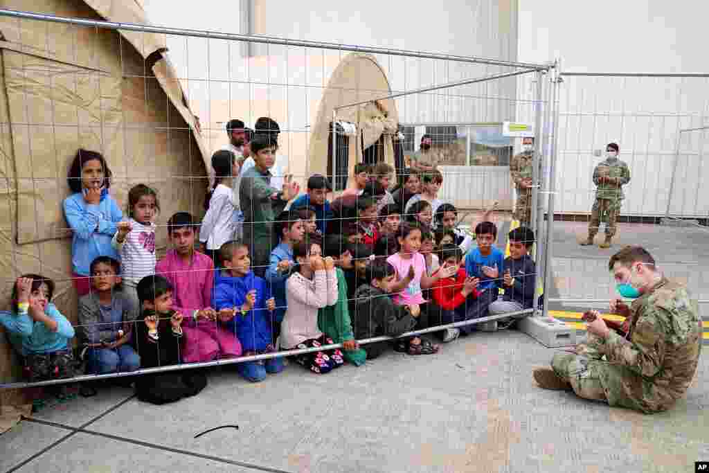 A U.S. soldier plays guitar for recently evacuated Afghan children at the Ramstein U.S. Air Base, Germany.